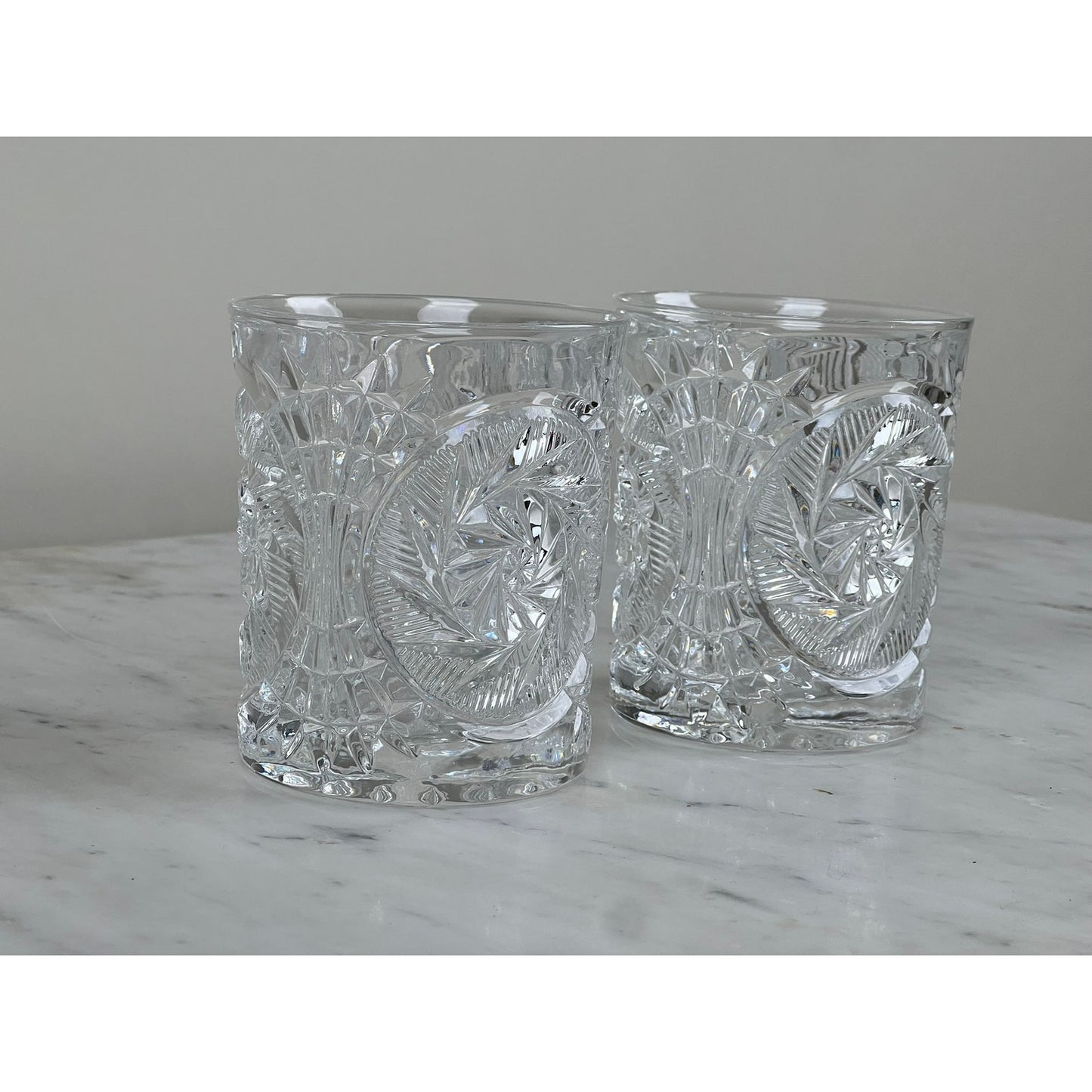 A pair of Fostoria Stowe Double Old Fashioned Tumbler Glasses are displayed on white marble with a plain light gray background.