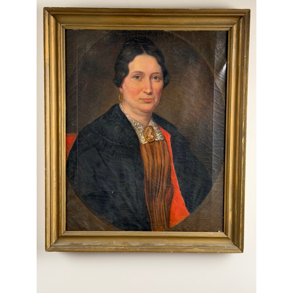 Oil portrait of a middle-aged woman in a black wrap and brooch, displayed in a gold-toned frame as part of a Pair of American School Oil Portraits of a Gentleman and Lady, c. 1840–1860, from Pearl City Antiques.