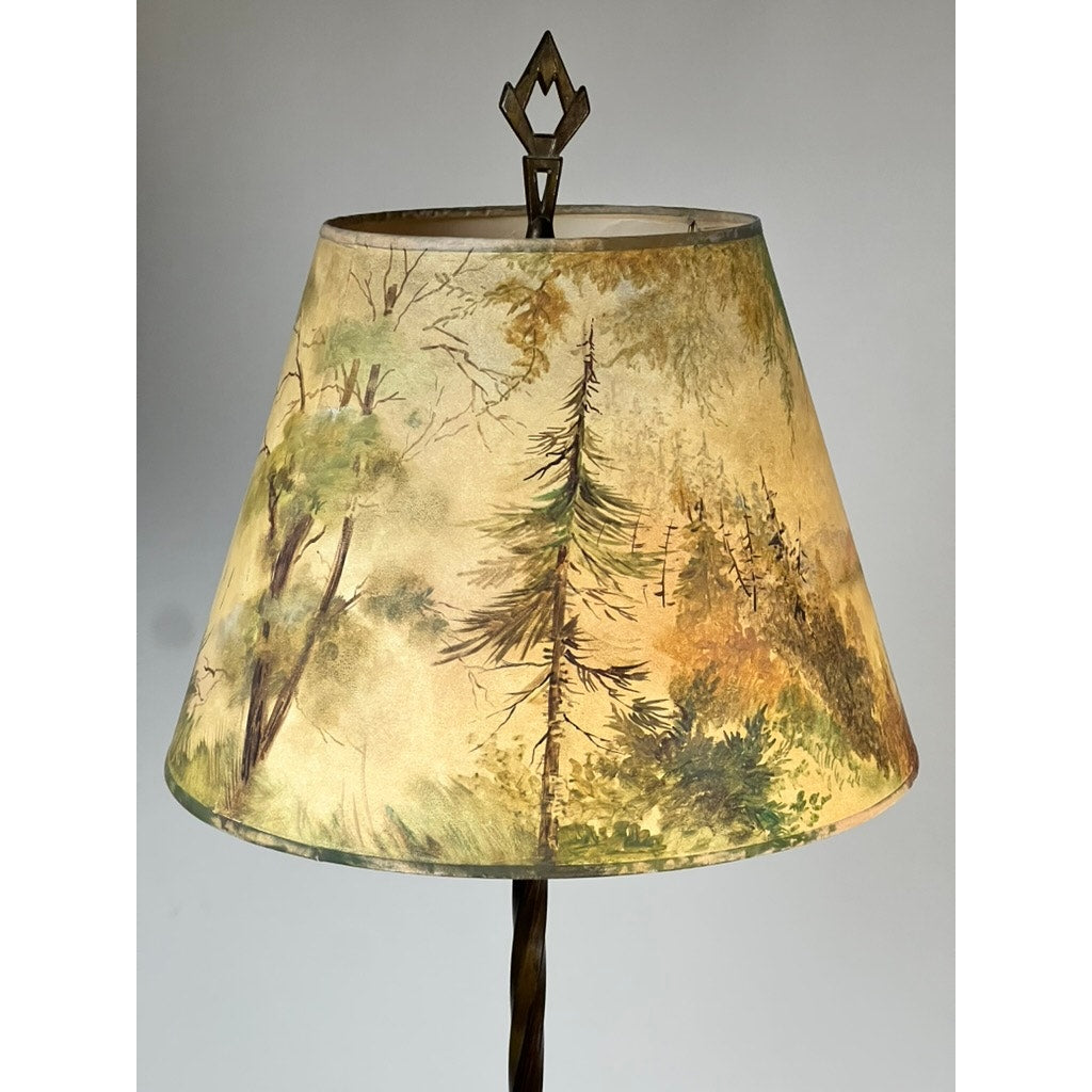 The Antique Art Deco Uranium and Slag Glass Lamp c. 1920 features a painted shade with scenic evergreens in earthy tones, topped by a geometric finial for a blend of vintage elegance and natural charm. Brand: None/Unknown.