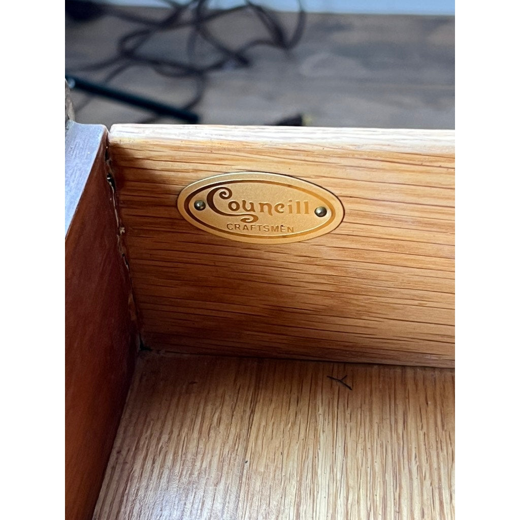 A close-up of a Vintage Solid Mahogany Chippendale Style Lowboy by Councill Craftsmen shows the wood grain and a brass oval label on the drawer corner, with blurred cables visible in the background.