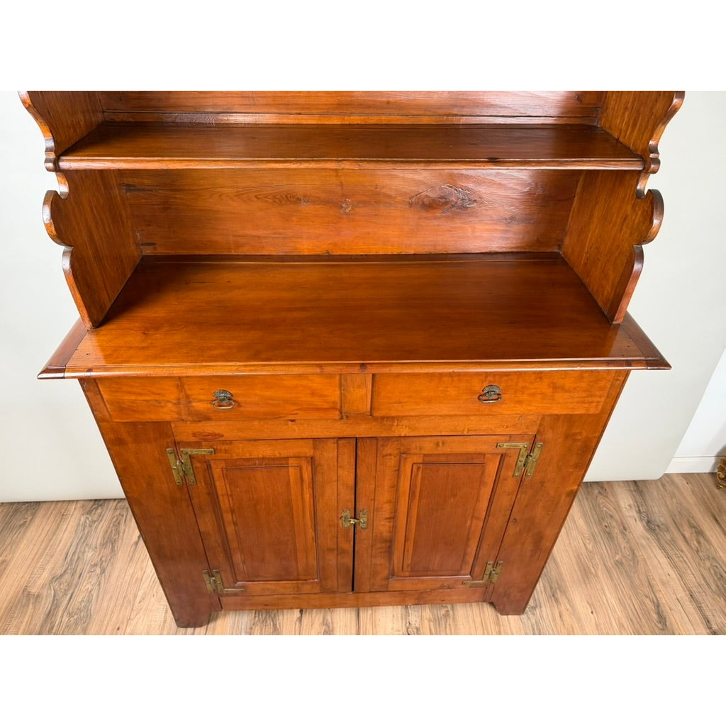 A tall Pennsylvania or Mid-Atlantic Cherry Open Pewter Cupboard, circa 1800–1830, with an open upper shelf, two drawers, and two lower cabinet doors with metal hardware.