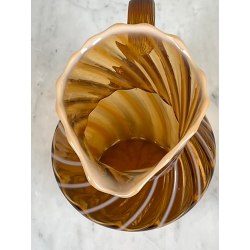 A top-down view of a Vintage Fenton Autumn Gold Opalescent Glass Spiral Pattern Pitcher with a wavy rim, shown on white marble—a stunning collectible with rich brown tones. Brand: None/Unknown.