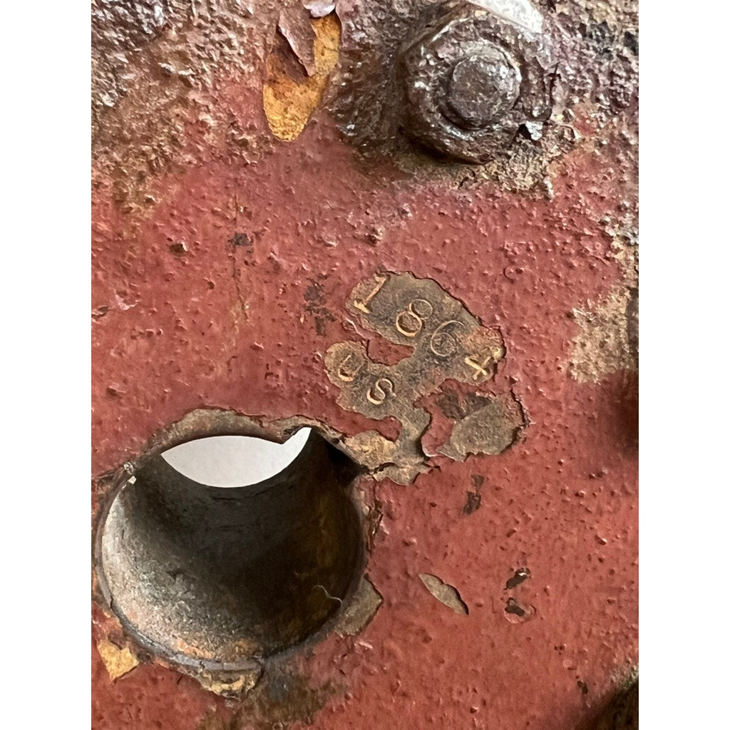 Close-up of an Antique Eight Spoke Mahogany and Iron Ship's Wheel stamped “1864 US," showing rusted red metal, peeling paint, and weathered details reminiscent of 19th-century maritime artifacts. Brand: Unknown.