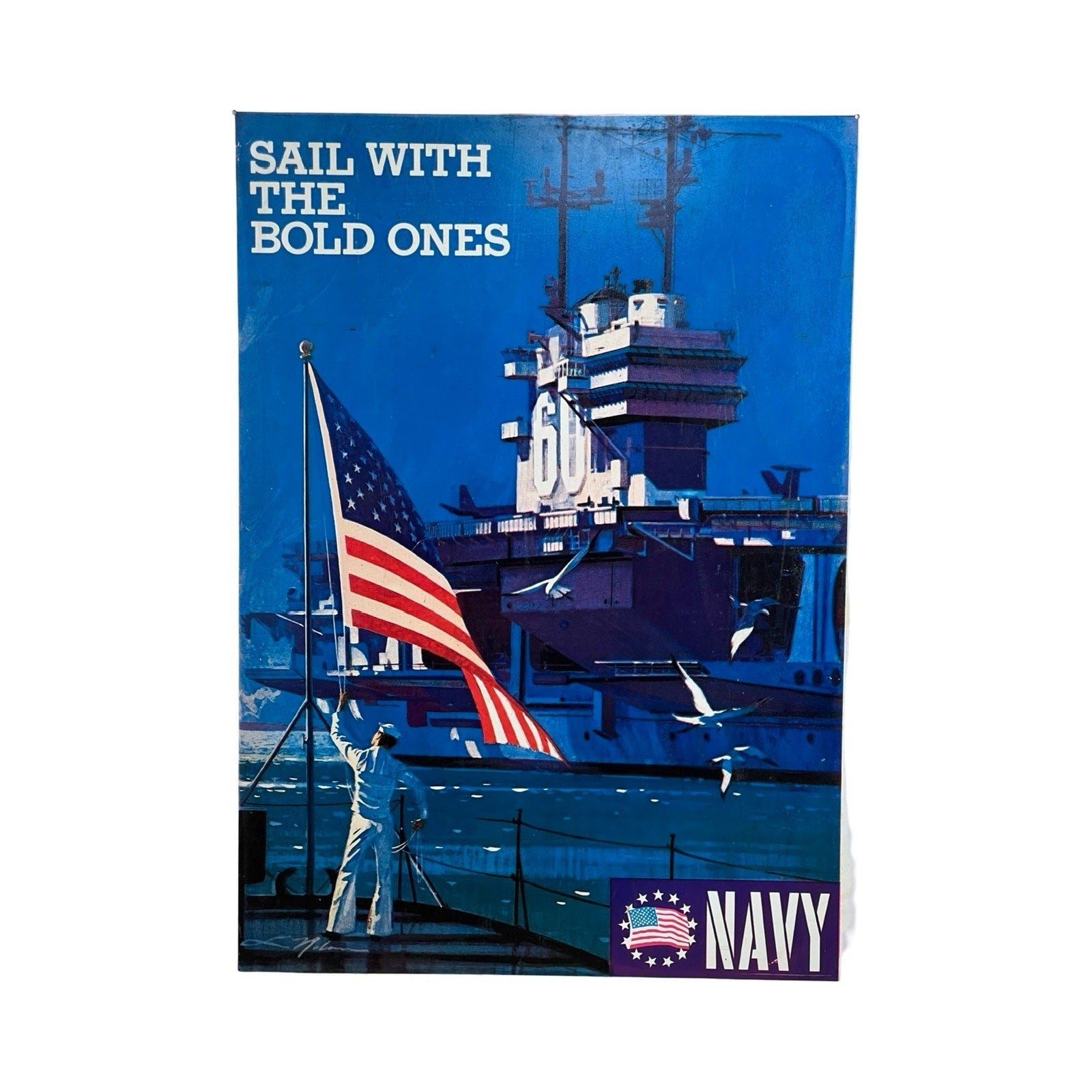 A sailor salutes the flag aboard ship, with the USS Saratoga aircraft carrier behind, echoing a Vietnam Era Navy recruiting sign by Lou Nolan. Text: "SAIL WITH THE BOLD ONES" and "NAVY." Blue hues dominate this double-sided tin sign.