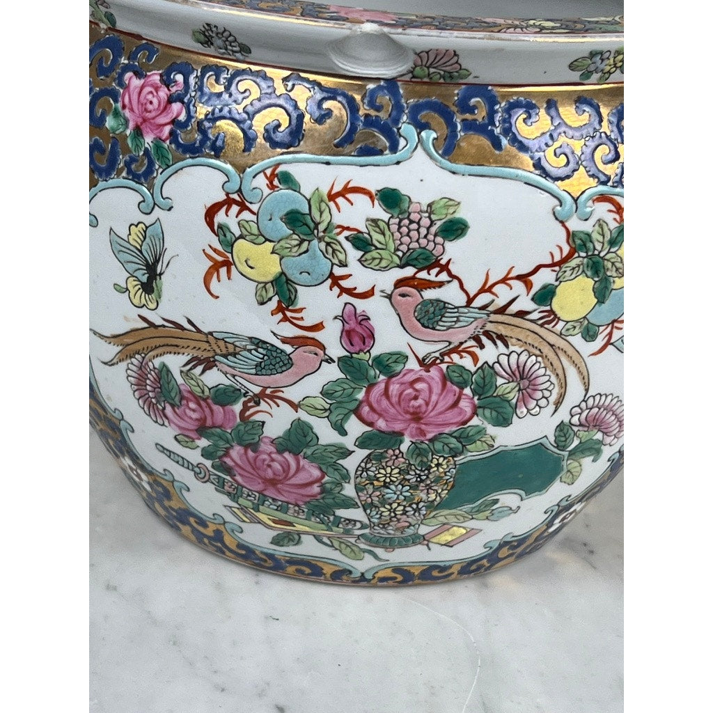 A close-up of the Vintage Chinese Famille Rose Fish Bowl Signed Minicucci, featuring intricate hand-painted flowers, birds, and leaves with cobalt blue and gold accents. This porcelain planter rests on a white marble surface.