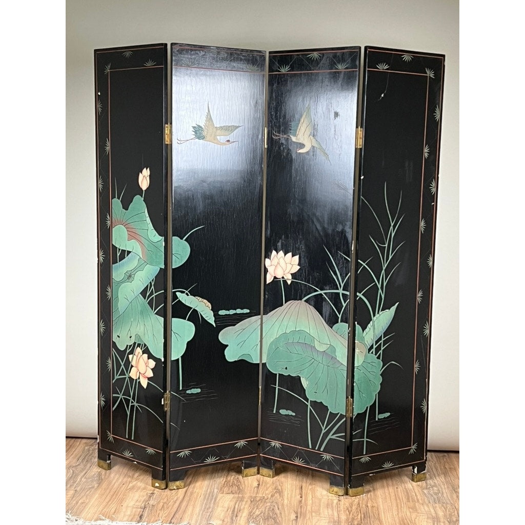 The Vintage Asian Black Lacquer Coromandel Room Screen features four panels decorated with painted cranes, green lotus leaves, pink lotus flowers, and reeds, and stands on a wooden floor against a plain light wall.