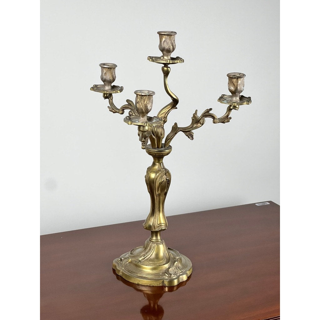A Vintage Brass Louis XV Style Four Light Candelabra with ornate Rococo revival detailing and curved branches sits on a polished wooden surface against a plain white background. Brand is unknown.