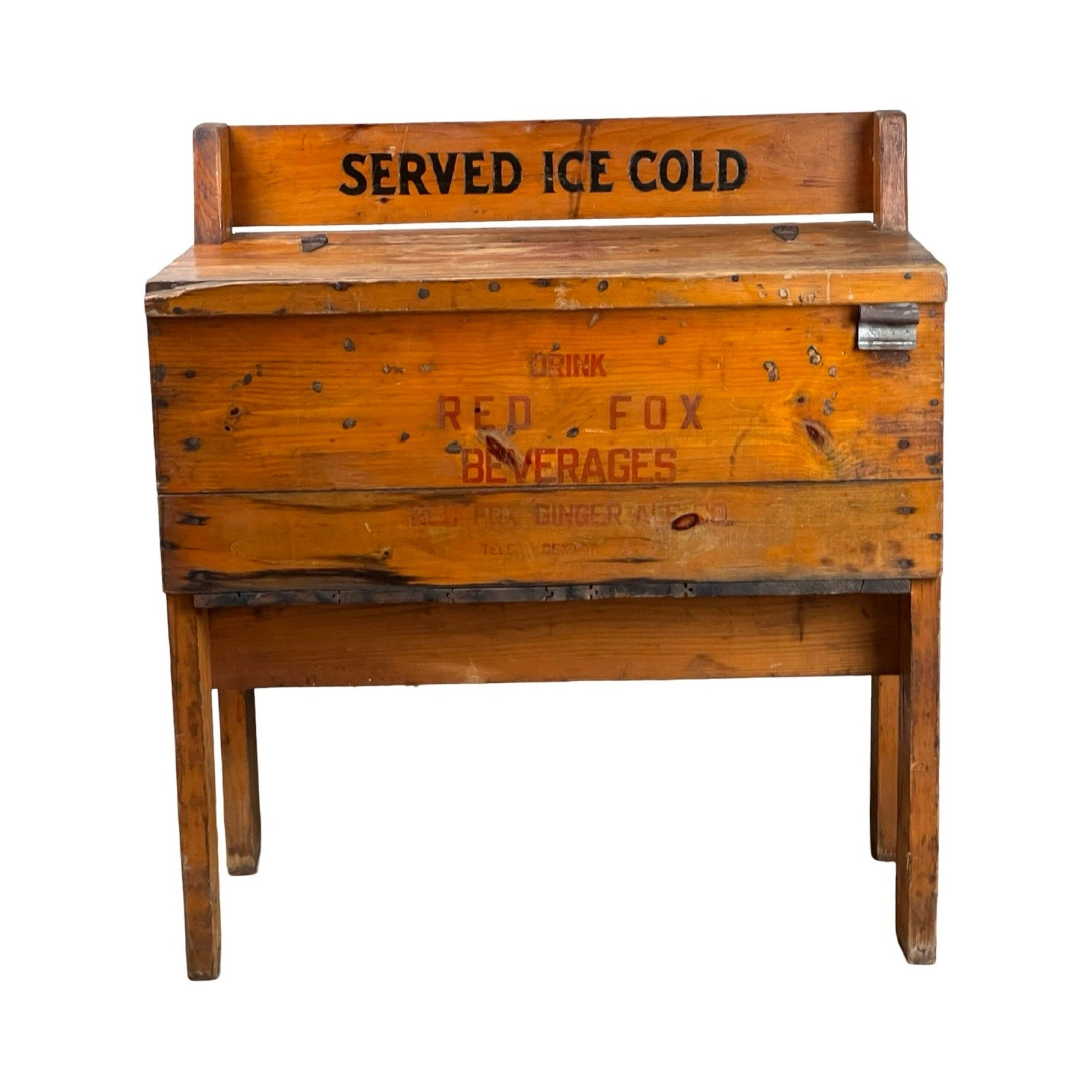 This Antique Tin Lined Pine Red Fox Ginger Ale of Rhode Island Cooler c. 1930 features "SERVED ICE COLD" on the backrest and "DRINK RED FOX BEVERAGES" on the front, standing sturdily on four legs against a white backdrop.
