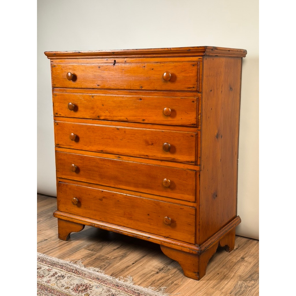 A Late 18th Century New England Pine Two-Drawer Blanket Chest by Pearl City Antiques, dating from c. 1780–1810, stands on a wood floor beside a patterned rug, evoking the warmth and charm of early American country furniture with its classic form and authentic antique finish.