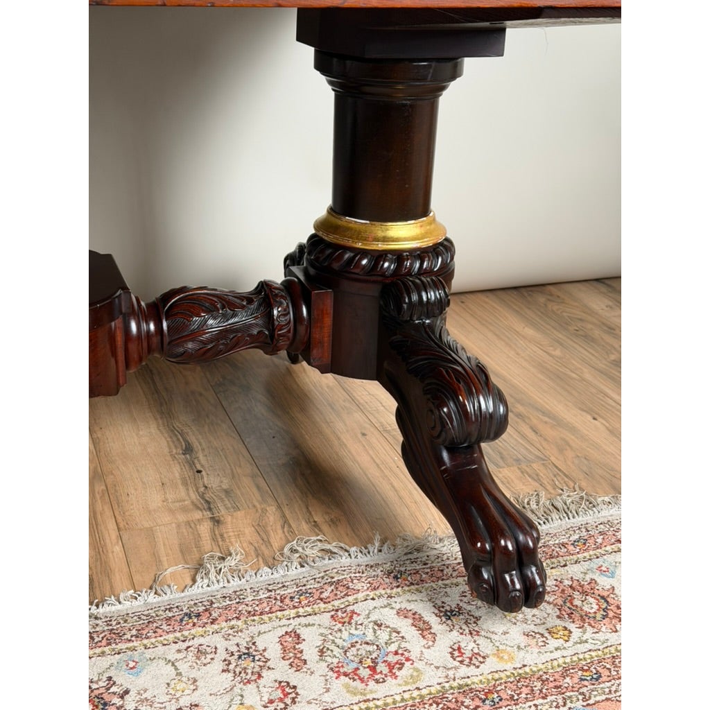 New York Classical Revival Carved Mahogany Double-Pedestal Library Table by Ernest F. Hagen, featuring a dark wood base with ornate carvings, a gold-toned collar, and carved animal-paw feet.