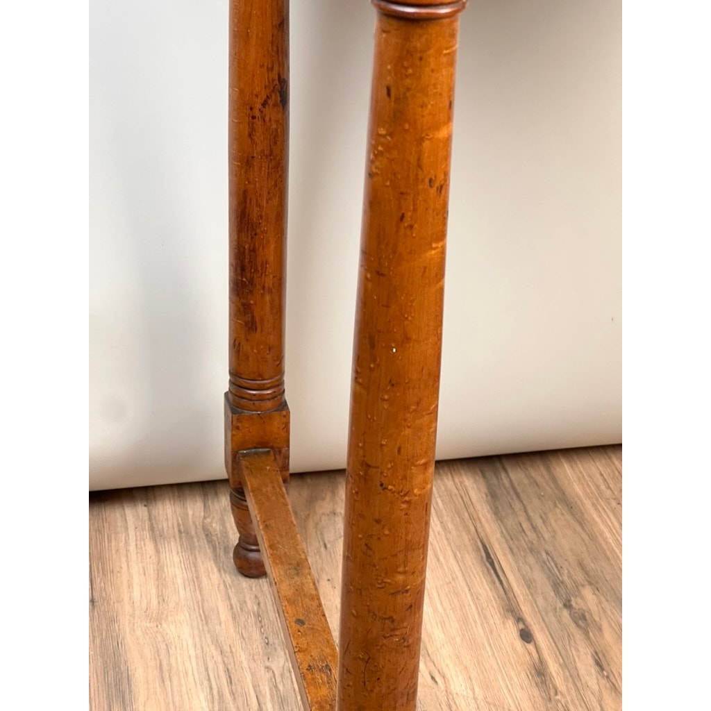 Close-up of two legs from an Antique Sheraton Birdseye Maple One Drawer Stand, early 19th century, showing their connecting support bar and warm brown finish with classic wear, set on a wooden floor against a plain white background.