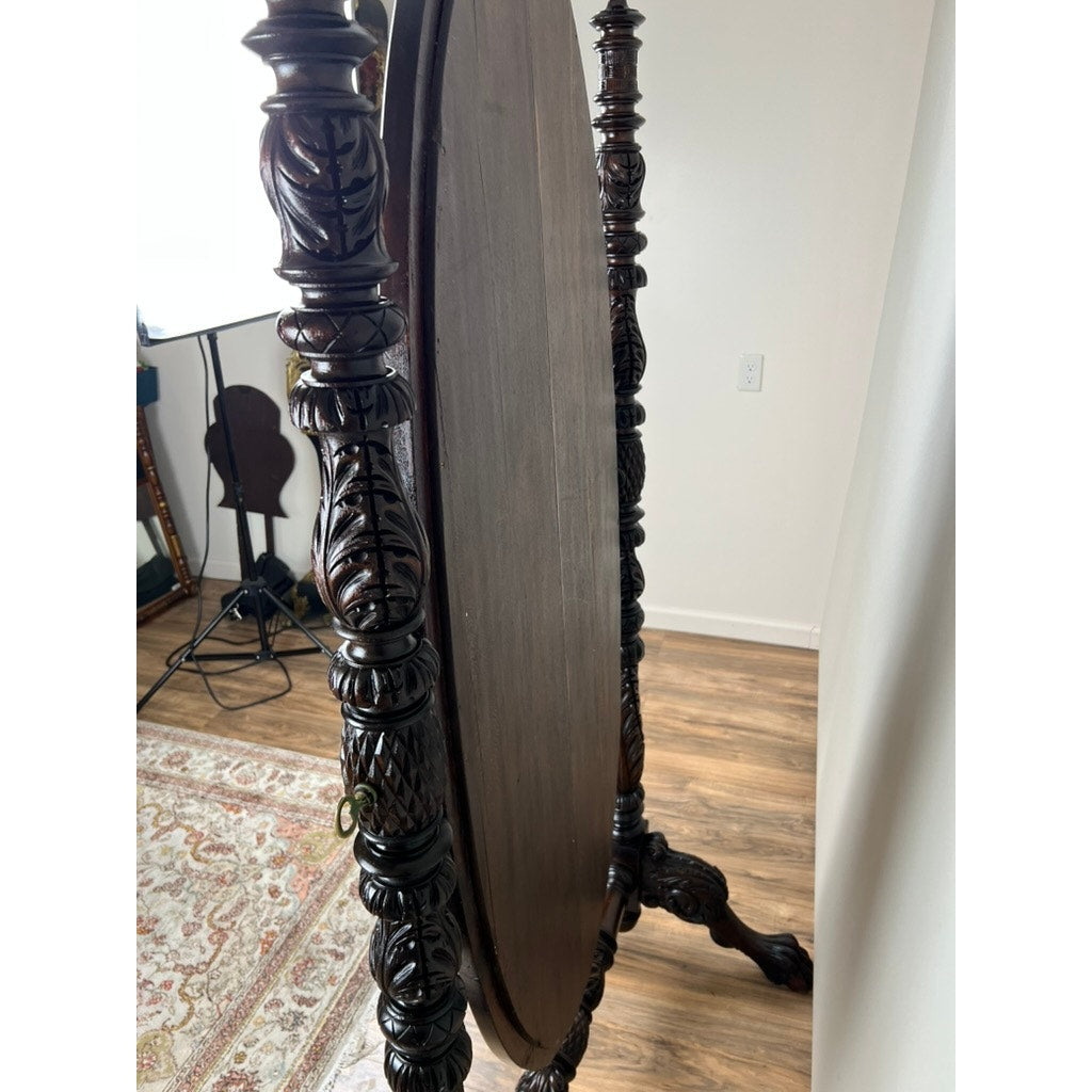 The Impressive Antique American Empire Acanthus and Barbola Rose Carved Cheval Mirror c. 1840 stands on a wooden floor near a patterned rug and white wall, highlighting 19th-century craftsmanship in a well-lit room.