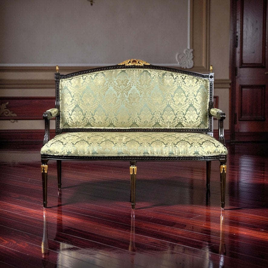A Vintage Louis XVI Style Settee in green damask upholstery stands on polished dark wood floors in an elegant room with decorative molding and a closed wooden door in the background.