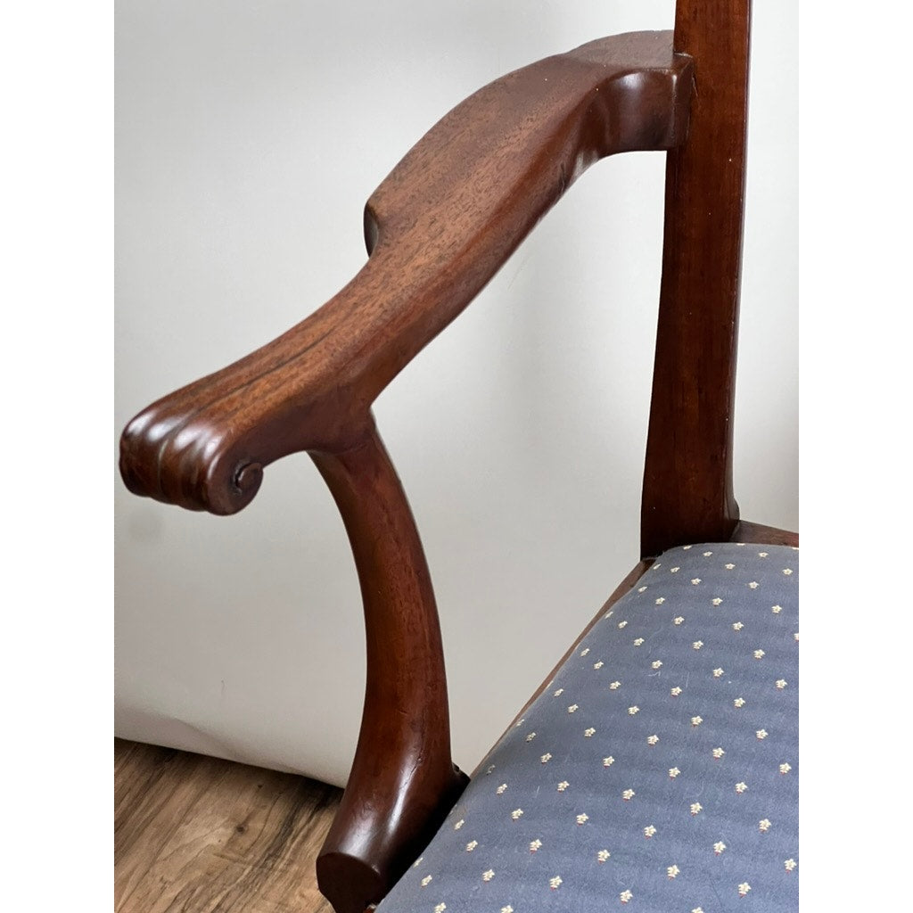 Close-up of an Antique Chippendale Walnut Open Arm Chair (Late 18th Century), showing the elegant carved armrest and curved design, attached to blue upholstery with a white floral pattern. The background is plain and light.
