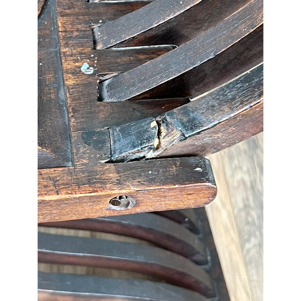 Close-up of an Antique Italian Renaissance Walnut Savonarola Chair (late 19th c.) with a broken slat, crack near the joint, scratched dark wood, and exposed screw. The chair sits on a light wood-grain floor. Brand: Unknown.