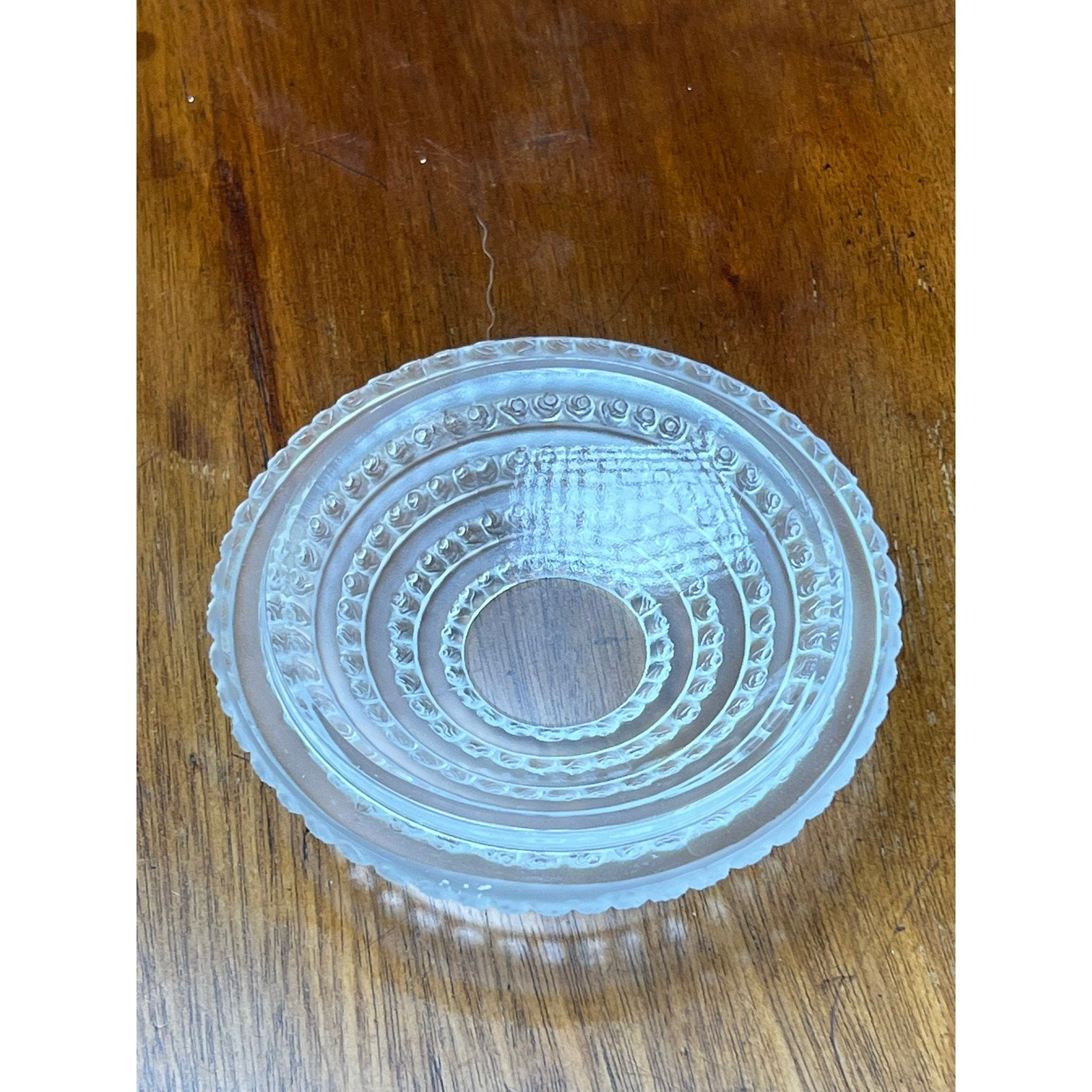 A Vintage Lalique Crystal Enfants Box by Lalique, featuring clear glass with concentric patterns and a scalloped edge, sits on a wooden surface.