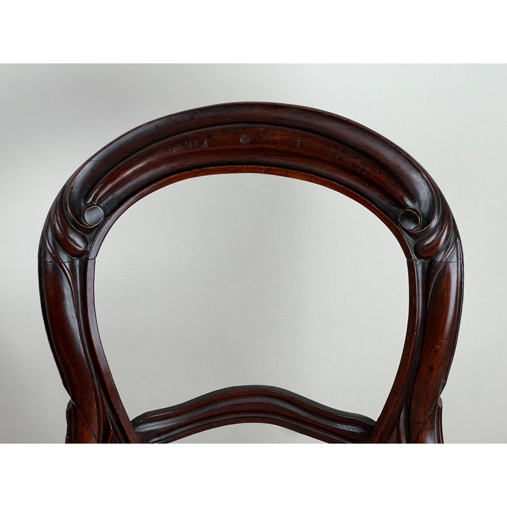 Close-up of the curved, carved wooden backrest on an Antique Pair Victorian Walnut Balloon Back Side Chair, showing intricate scrollwork and a polished dark brown finish against a plain light background. Brand: Unknown.