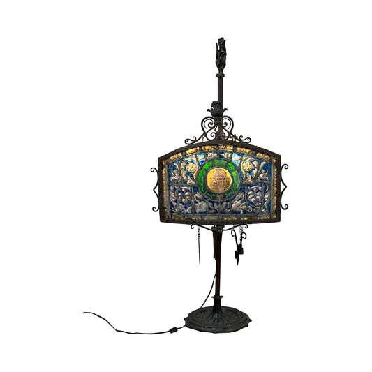 Antique Five Burner Lucerne Whale Oil Lamp with Napoleon I Fireplace Screen Shade features colorful blue, green, and gold patterns on a rectangular shade atop a dark metal stand with round base and visible power cord. Brand unknown.