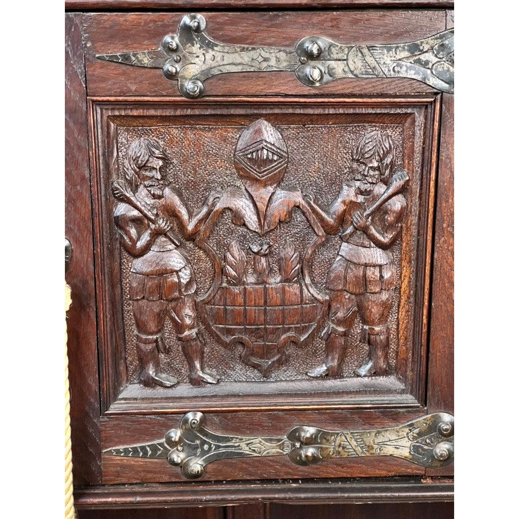 Antique 19th-century French Breton-style carved oak cabinet features deeply carved knights, a central crested helmet, and ornate corner hinges—a striking example of historic craftsmanship.