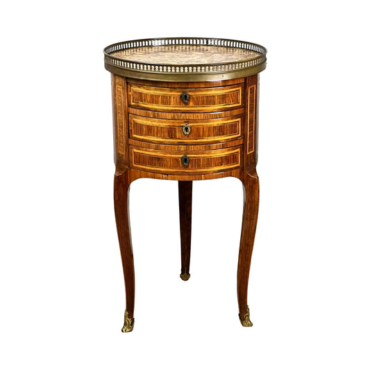 An Antique French Louis XV Kingwood Parquetry Chiffonière Table, c. late 18th century, attributed to François-Antoine Mondon, with three drawers, brass handles, tapered legs, and a brass gallery around a marble top on a white background.