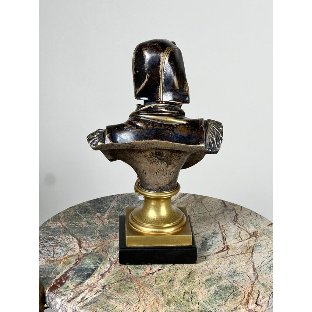 Patinated bronze sculpture of Michelangelo by Albert-Ernest Carrier-Belleuse, modeled before 1883 in Paris, shown from behind atop a gold and black pedestal. Displayed on a round marble-topped table with gray, brown, and red veining.