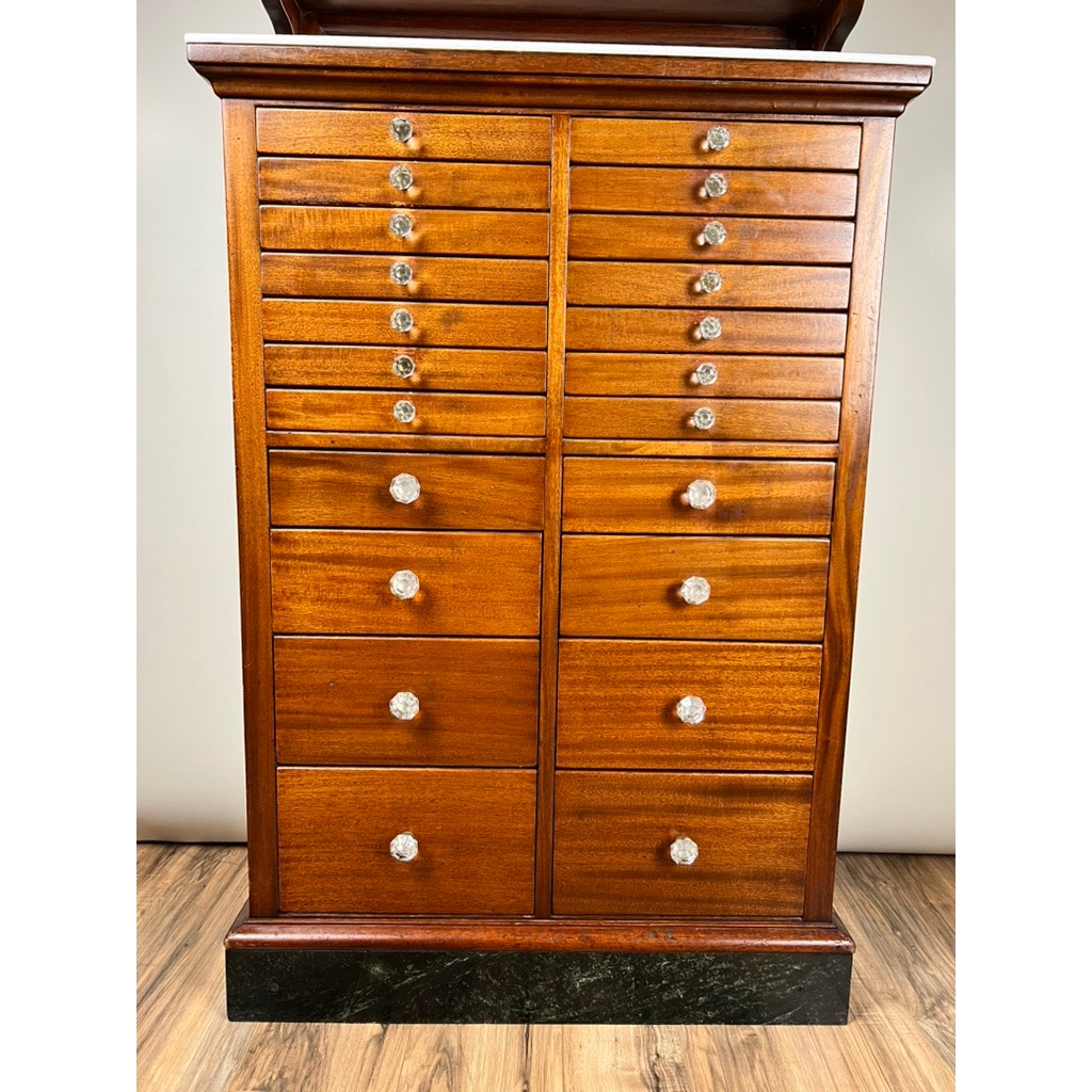 An early 20th-century Antique Mahogany Multi-drawer Dental Cabinet by The American Cabinet Co. features double columns of drawers with glass knobs, set on a dark base against a light wall and wooden floor.