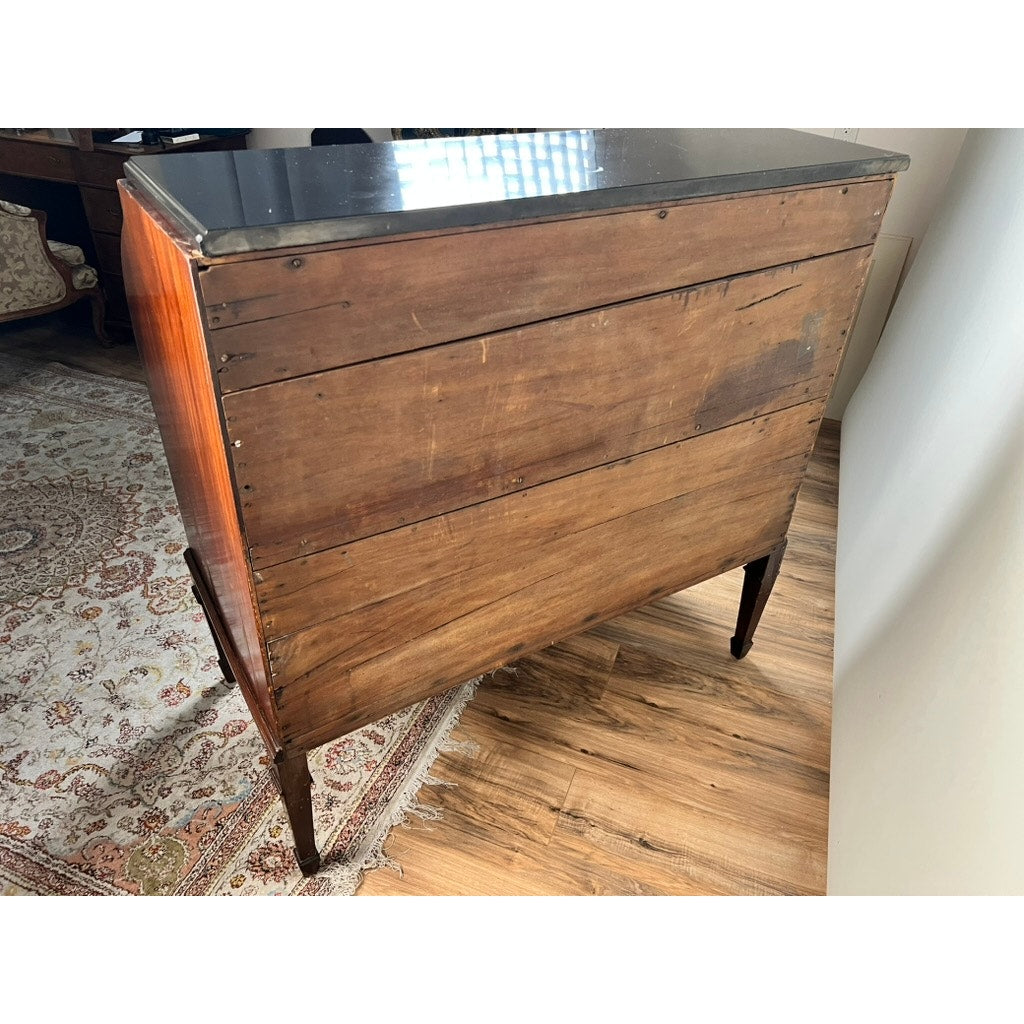 An Antique Directoire Style French Cylinder Desk with a slate top from the late 19th century, viewed from the back, features horizontal wooden panels and metal fasteners. It stands on four legs near a wood floor, patterned rug, and window.