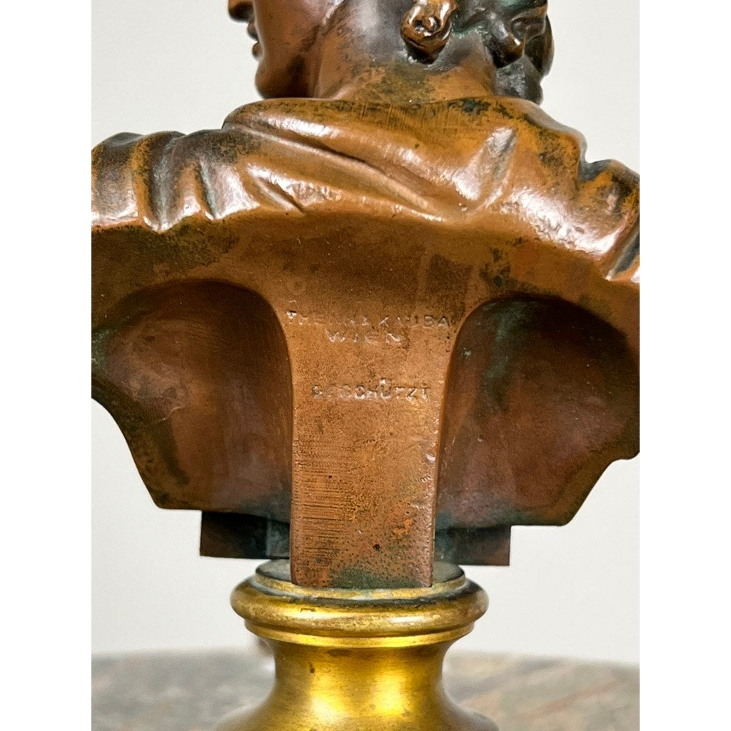 Close-up of the back of an Antique Small Bronze of “the Apollo Belvedere” with Vienna Foundry Mark, engraved base details, partial view of a person's head and shoulders, and a round metallic pedestal underneath.