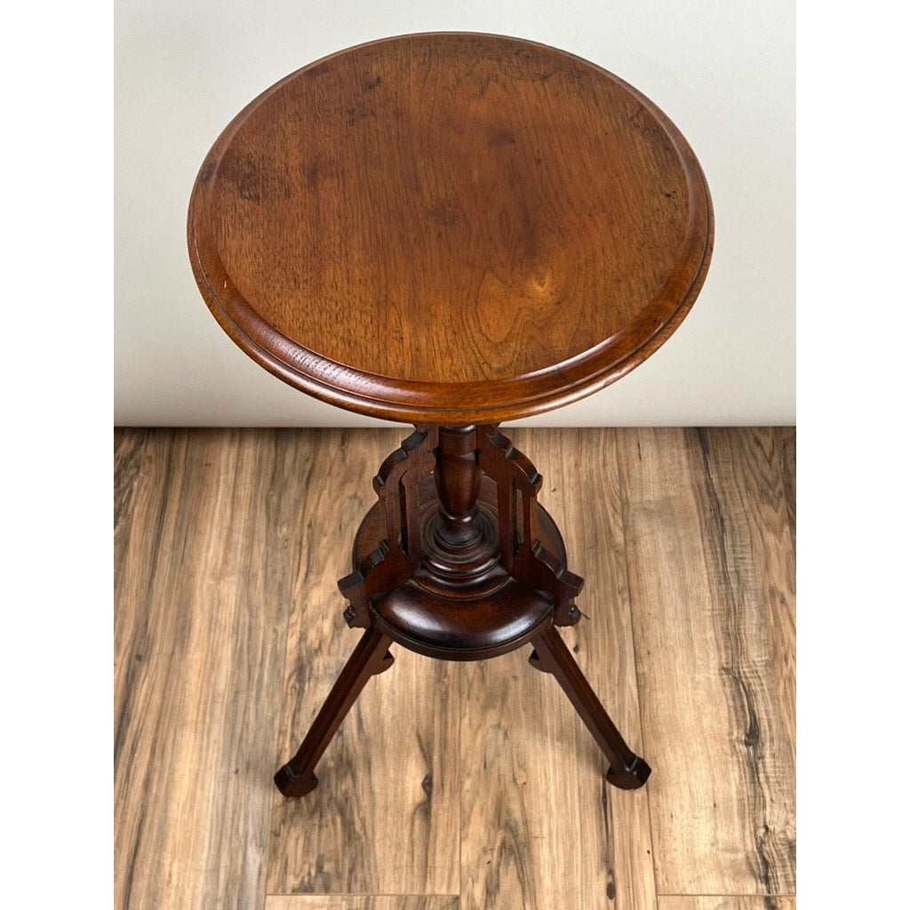 An Antique Victorian Walnut Candle Stand, late 19th century, with a polished round top and tripod base, is displayed on a light wood floor against a plain white background, capturing classic period elegance. Brand unknown.