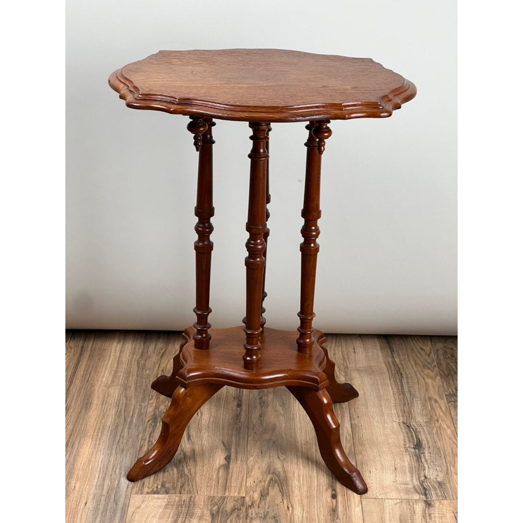 An Antique Victorian Walnut Turtle Top Candle Stand from the late 19th century features a scalloped edge, three turned legs, and a three-footed base. Shown on a hardwood floor against a light-colored wall. Brand: None/Unknown.
