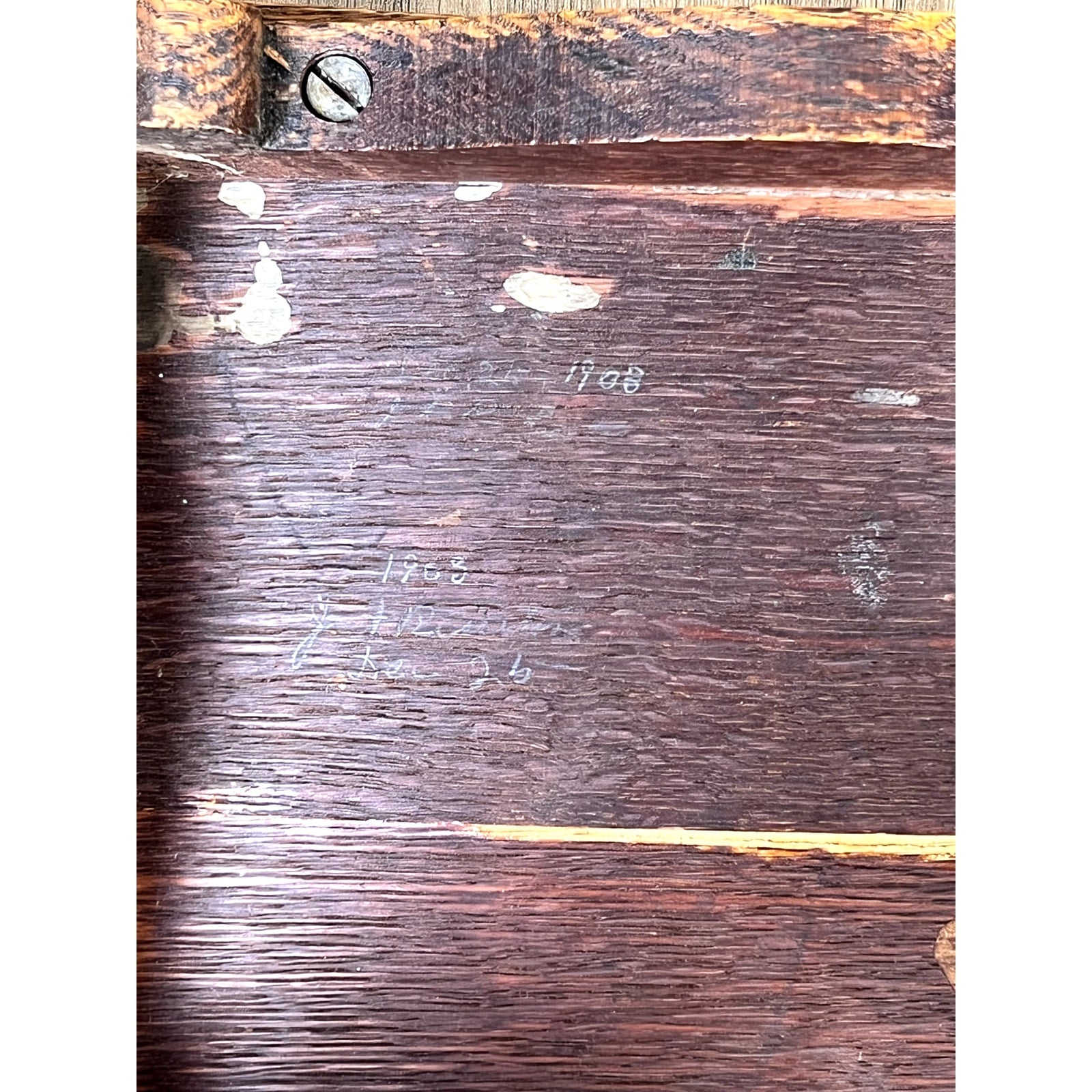 A close-up of the Antique Arts and Crafts Saddle Shaped Footstool c. 1900 shows its worn dark wood, visible grain, scratches, scattered white paint marks, faint pencil markings, and the number 1908 on the surface. Brand: None/Unknown.