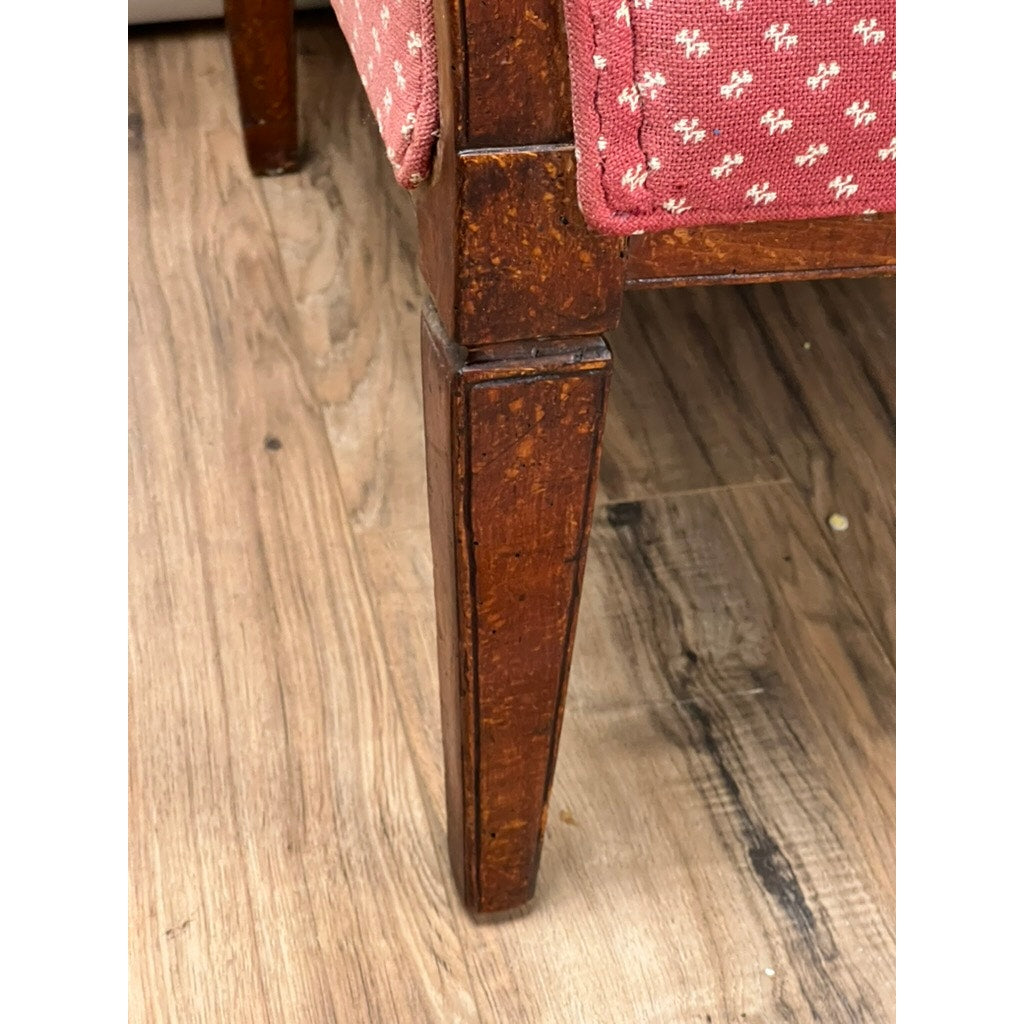 Wooden chair leg with pink floral cushion on a wooden floor