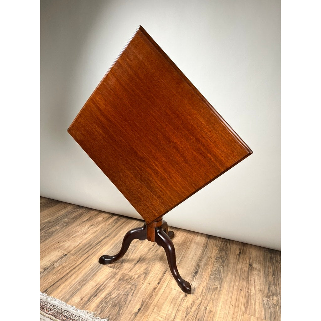 An Antique Queen Anne Mahogany Tilt Top Breakfast Table, c. late 18th century, with a square diagonal top and three-legged pedestal base, stands on a wooden floor against a plain light wall.