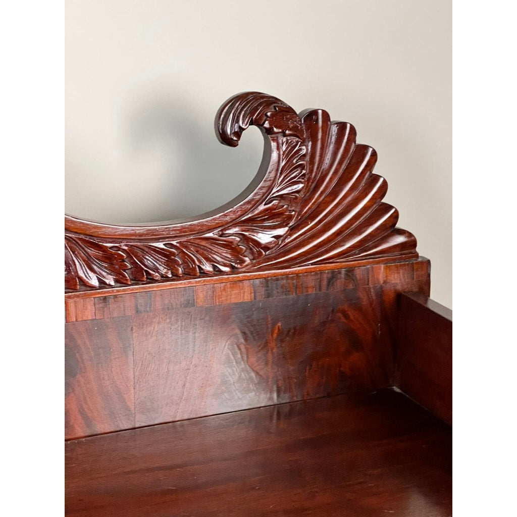 Close-up of an Antique American Empire Mahogany Sideboard with rosewood edge banding, probably Philadelphia c.1840, showing ornate carved swirl and leaf patterns on the top edge against a plain light background.