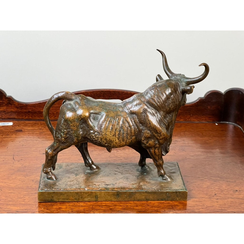 The Jean-Baptiste Clesinger “Taureau Romain” Bronze Sculpture, cast by Barbedienne Foundry in Rome in 1858, displays a bull with prominent ribs and muscles on a rectangular base set atop a wooden surface with a curved decorative back.