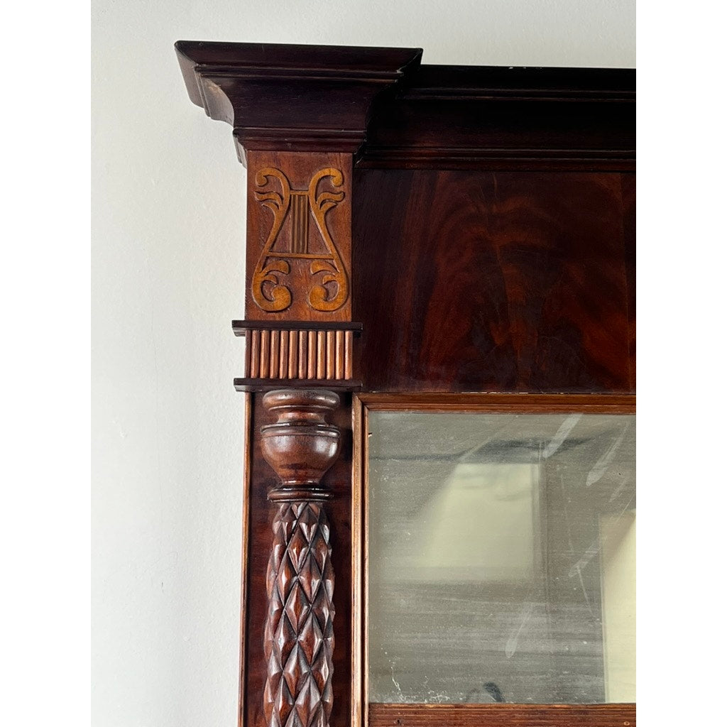 Close-up of the Antique American Empire Mahogany Pier Mirror c. 1840, highlighting its ornate lyre motif and detailed column carvings beside a reflective glass panel—an exquisite mid-19th century design detail.