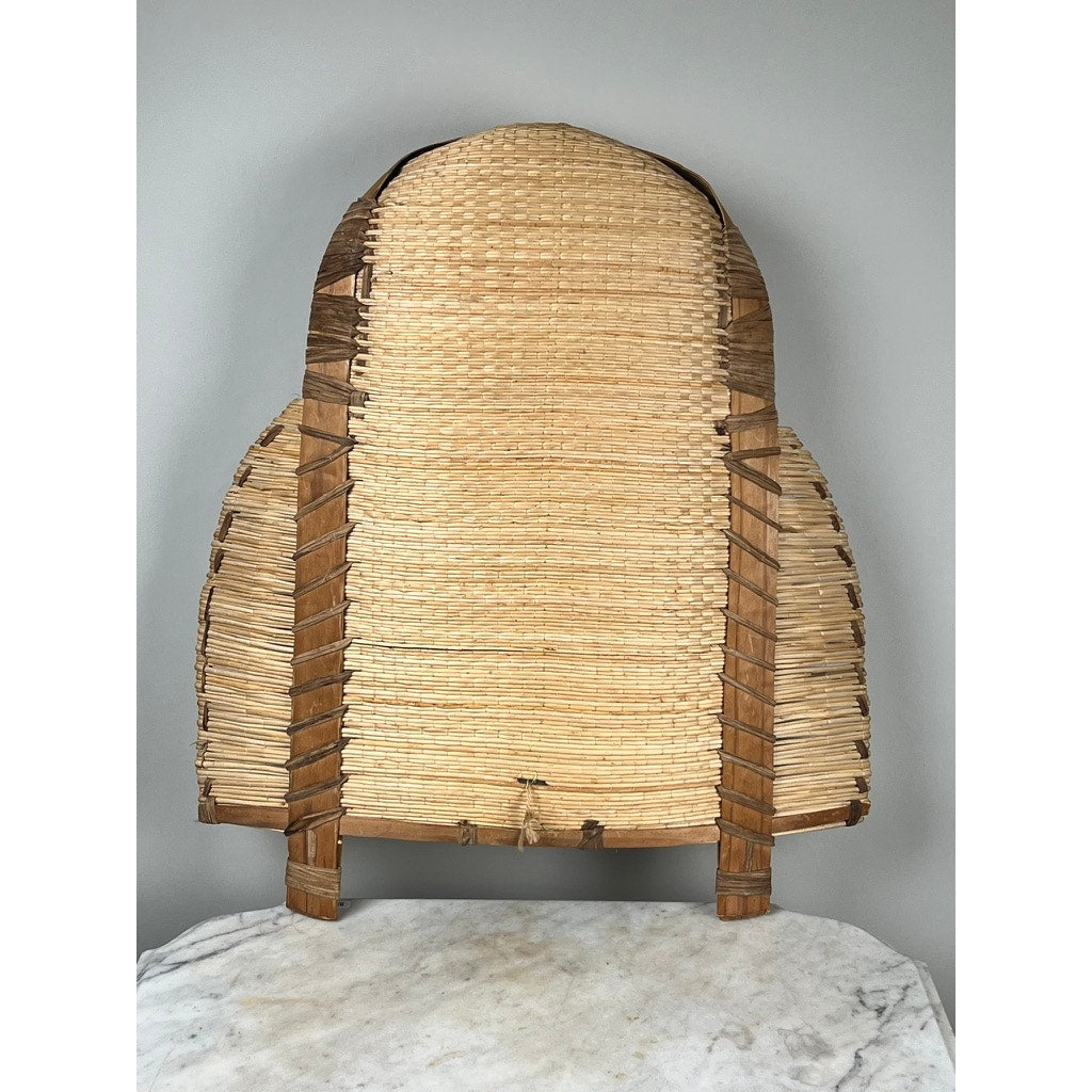 The Vintage Traditional Winnowing Basket, handwoven from natural fibers with wooden supports, stands on a marble surface against a plain gray background—ideal for adding vintage decor charm to your space.