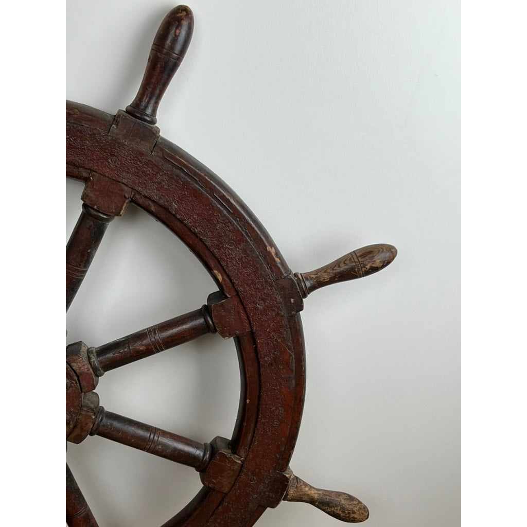 A close-up of part of an Antique Eight Spoke Mahogany and Iron Ships Wheel stamped “1864 US,” showing four worn handles against a white background, highlighting its unique 19th-century maritime craftsmanship. Brand: None/Unknown.