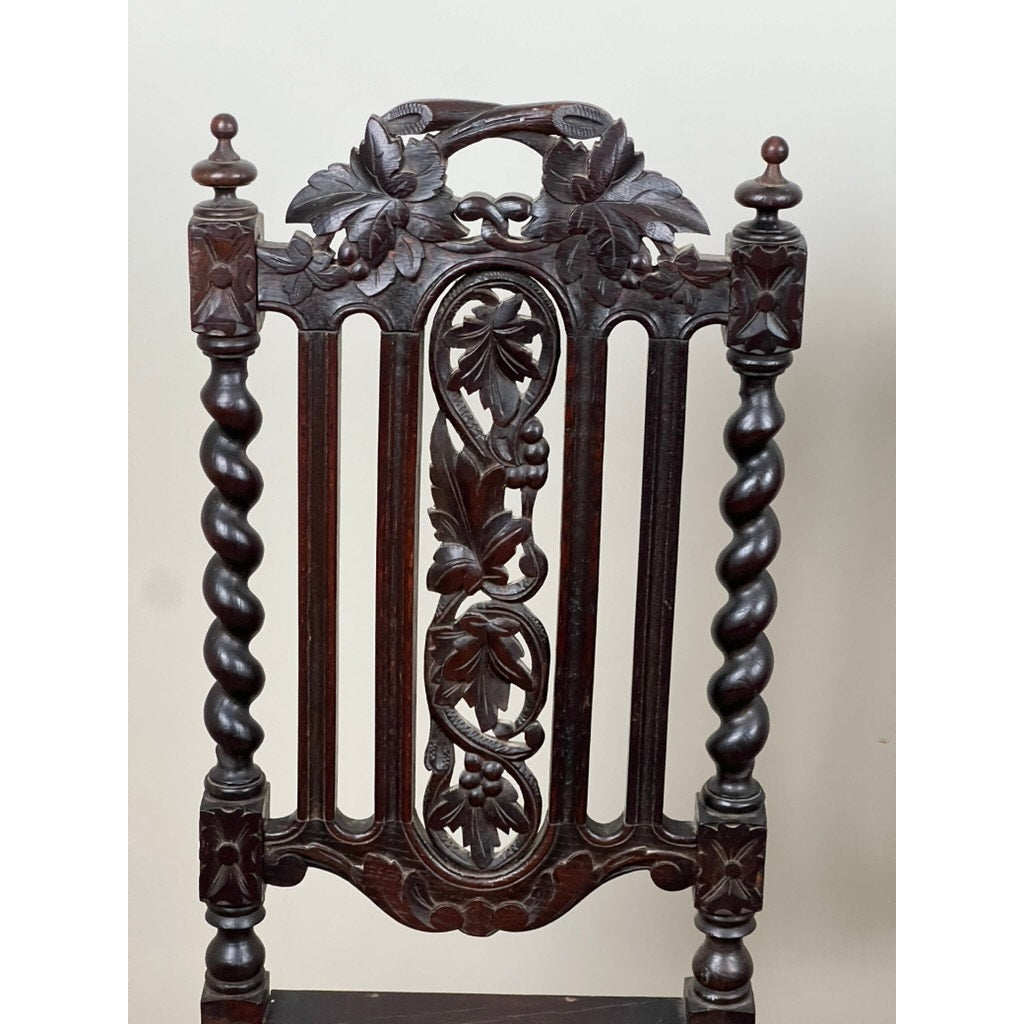 A pair of antique French walnut hunting chairs from the late 19th century, featuring ornate leaf and fruit carvings, spiral-twist side columns, and a decorative top in the Renaissance Revival style. Brand: None/Unknown.
