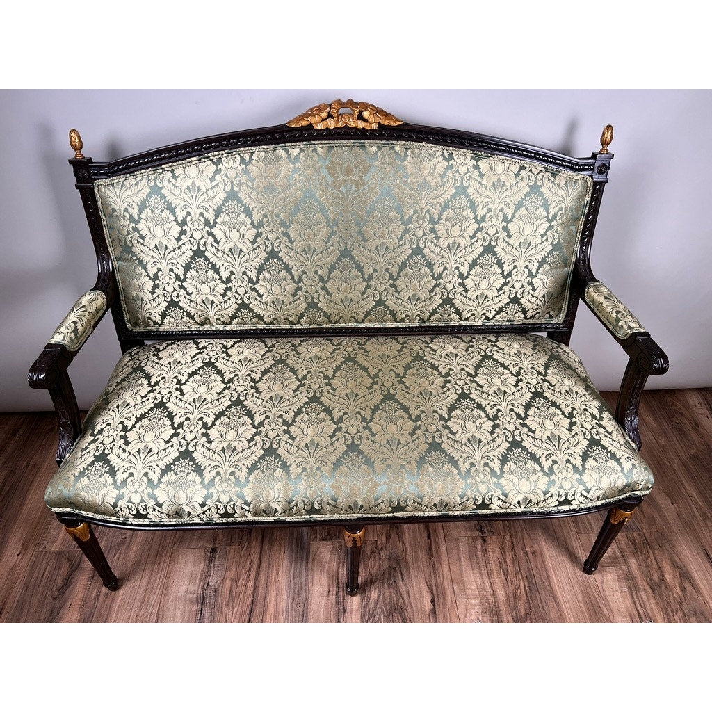 The Vintage Louis XVI Style Settee in Green Damask Upholstery features a dark wood frame with gold accents, set on a wooden floor against a plain wall. Brand: None/Unknown.
