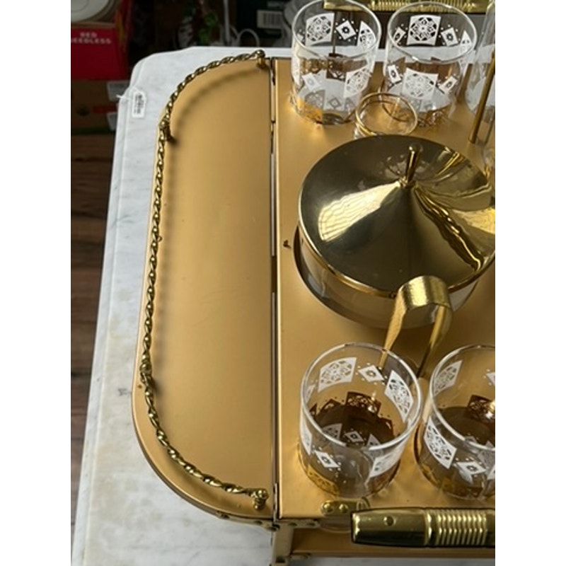 A close-up of a Vintage Mid Century Modern Bar Caddy c. 1960s holds a gold teapot and several clear glasses with white patterns, all placed on a white surface. Brand: None/Unknown.