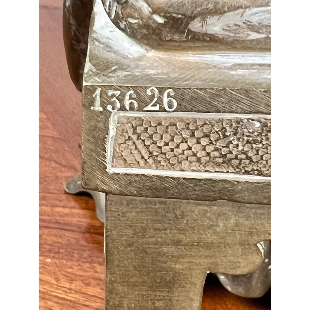 Close-up of the Antique Bronze Sculpture “Teacher and Pupil” by Louis Charles Janson (1865, signed Ch. Janson), showing the engraved number 13626 above a textured section, displayed on a wooden surface. Brand unknown.