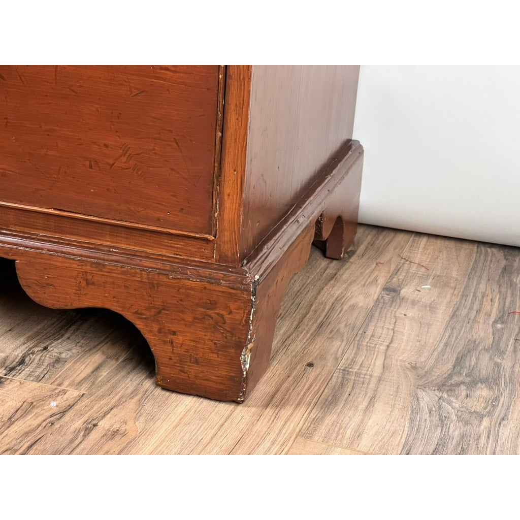Close-up of the lower corner of an Antique Chippendale Pine Graduated Four Drawer Chest (c. Late 18th Century, attr. Northampton MA maker) with scuffed edges, scratches, carved feet, and a rich reddish-brown finish on a wood-patterned floor.