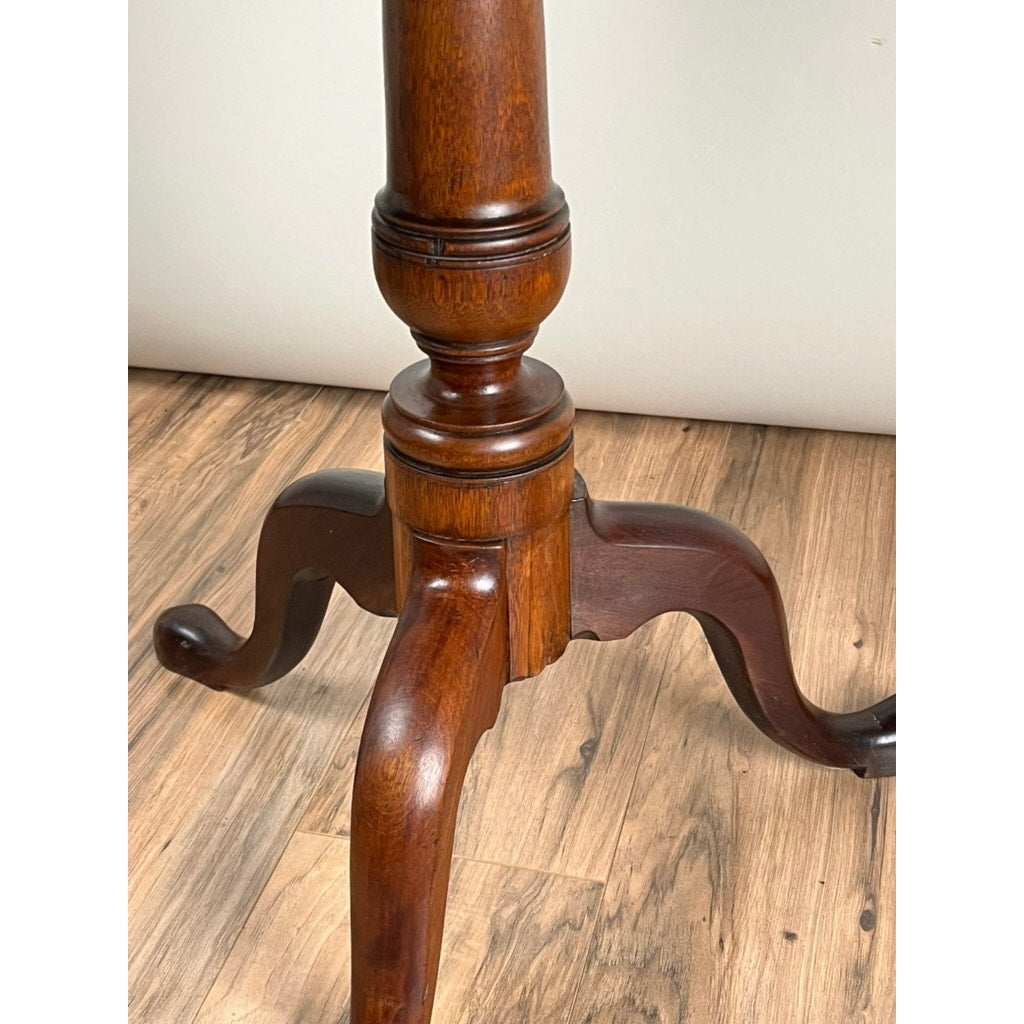 Close-up of the base of an Antique Queen Anne Mahogany Tilt Top Breakfast Table, late 18th century, featuring three curved feet on a light brown wood floor against a plain white wall. Brand: None/Unknown.