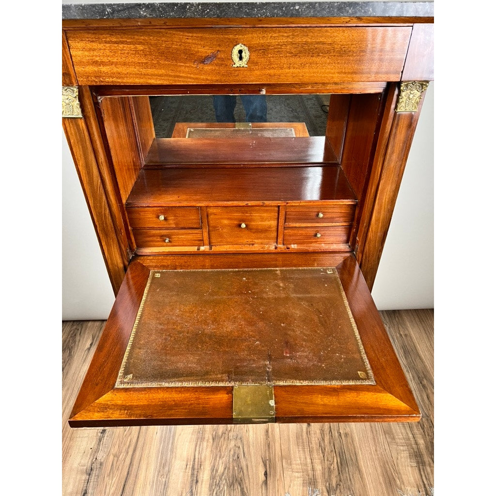 An Antique French Empire Secrétaire Abattant with ormolu mounts, c. mid-19th century, featuring a mahogany veneer, leather writing surface, interior mirror and drawers, and brass hardware. Front panel open on wood floor. Brand unknown.
