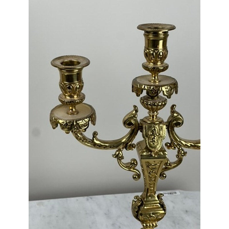 A close-up of an Antique Pair Late 19th Century Brass Three Light Candelabra with ornate detailing, displayed on a white marble surface against a plain light background. Brand: None and/or Unknown.