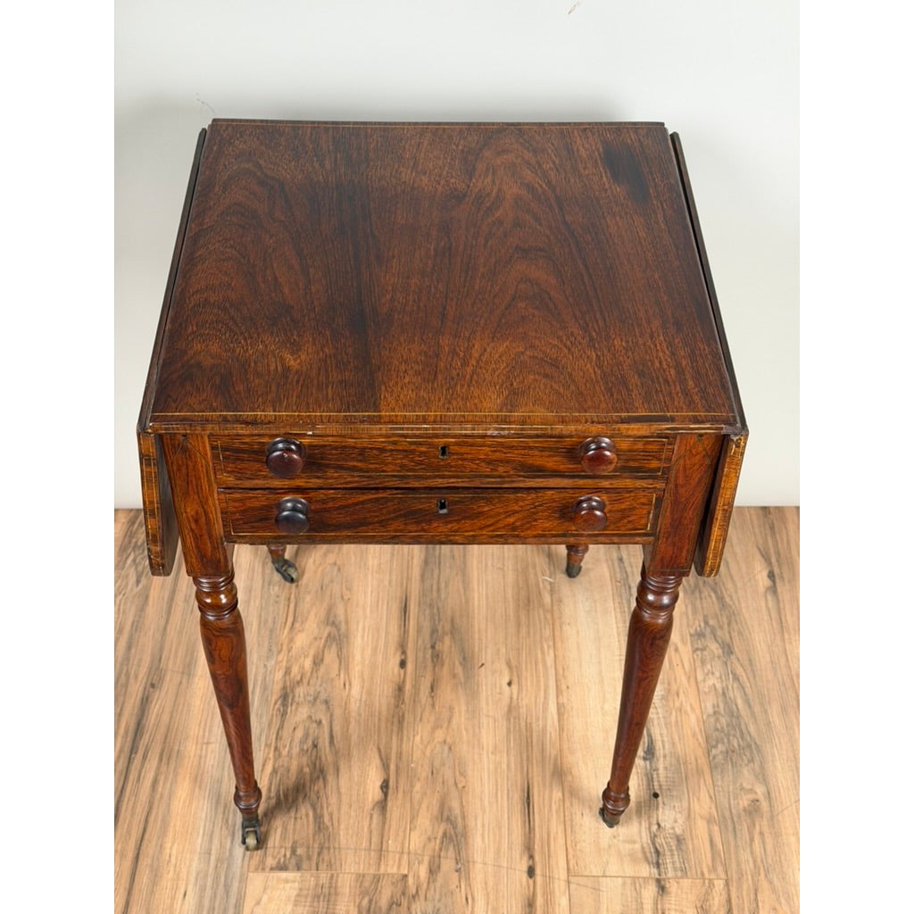 English Regency Rosewood Two-Drawer Drop-Leaf Work Table with Brass and Satinwood Inlay, a dark wood piece with two drawers featuring round knobs and inlay detailing.