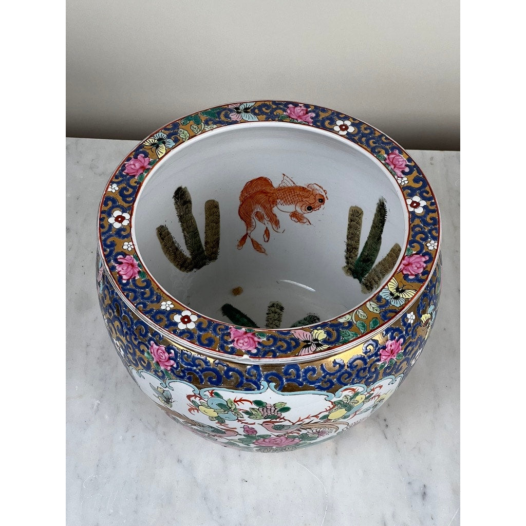 The Vintage Chinese Famille Rose Fish Bowl Signed Minicucci features intricate floral patterns and an orange fish motif, making it a striking decorative accent on any marble surface.