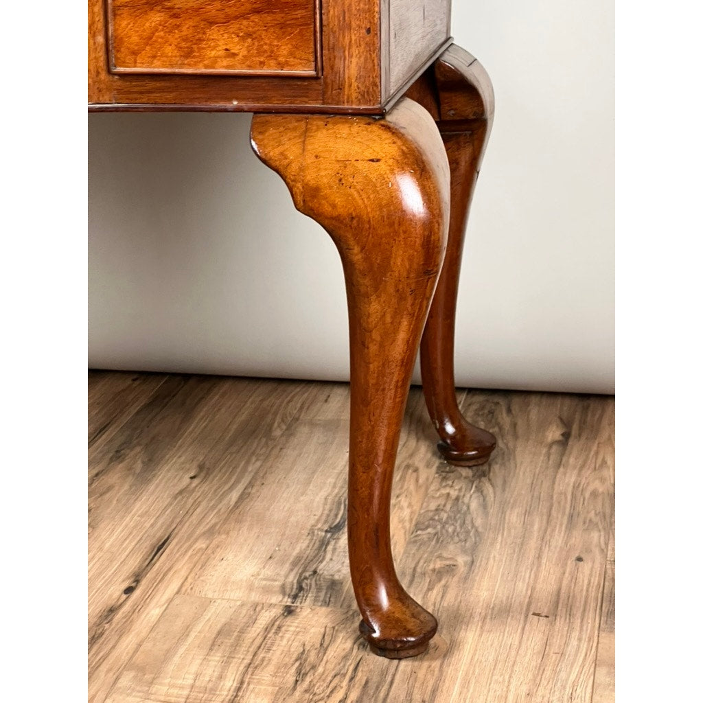 Close-up of the curved wooden legs of an Antique George III Queen Anne Mahogany Lowboy (c. Late 18th Century) with cabriole design, set on a wooden floor against a neutral background. Brand: Unknown.