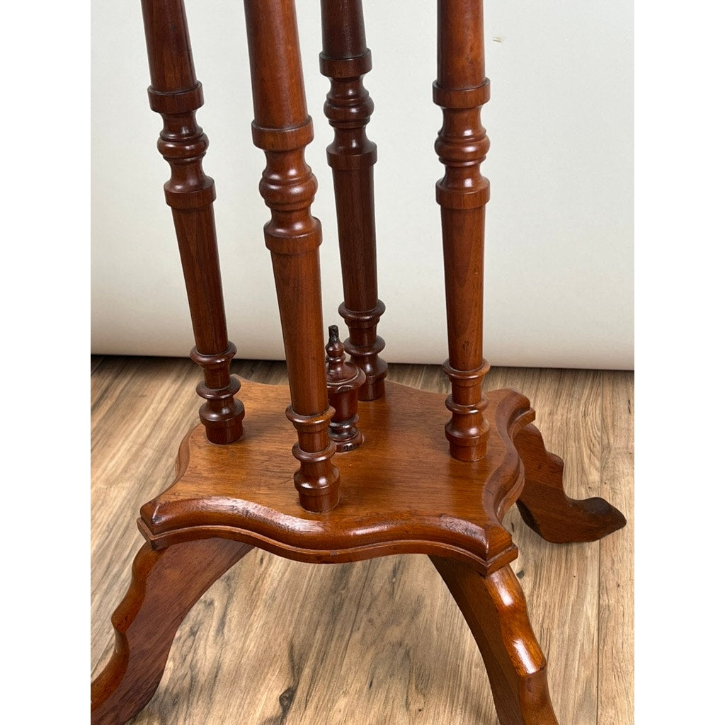 Close-up of the base of an Antique Victorian Walnut Turtle Top Candle Stand (late 19th century) with intricately carved legs and turned columns, shown on a wood floor against a plain light background. Brand: None/Unknown.